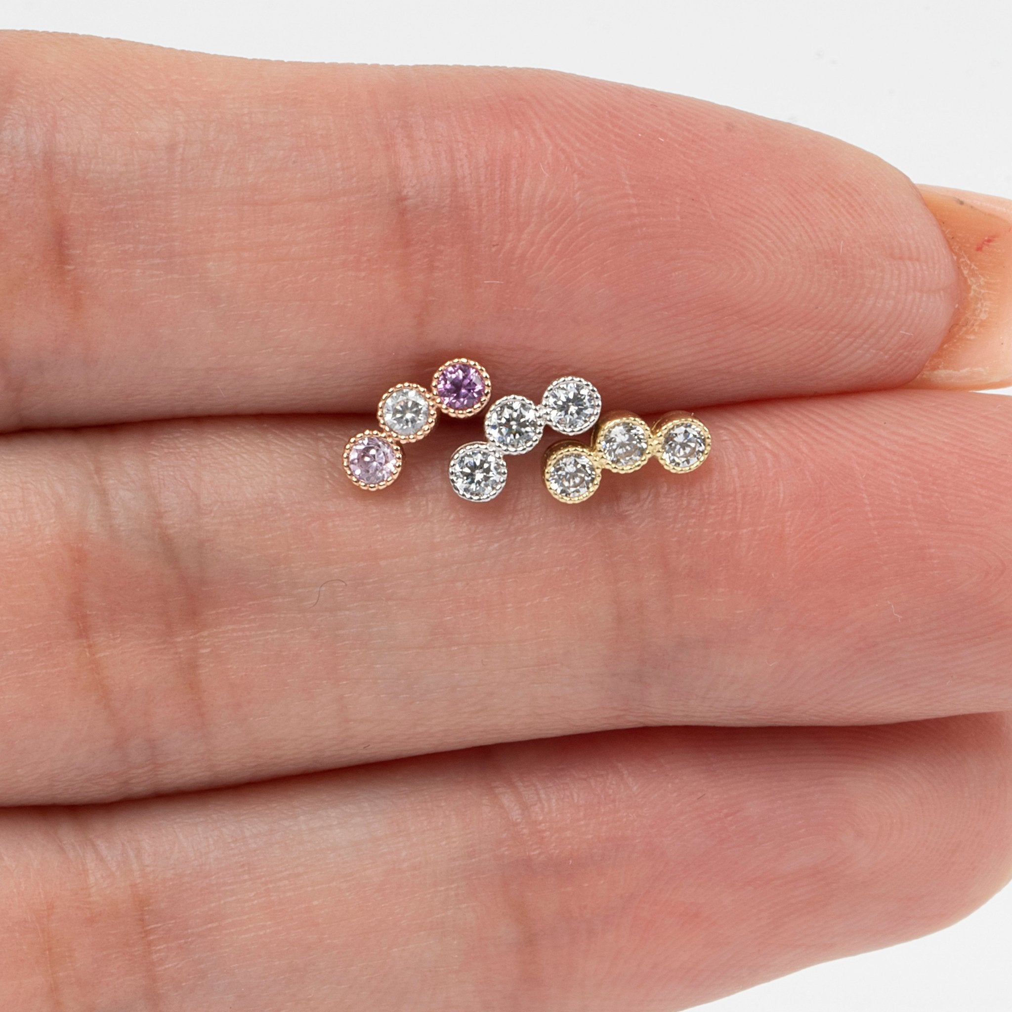 a person's hand holding three different colored stones