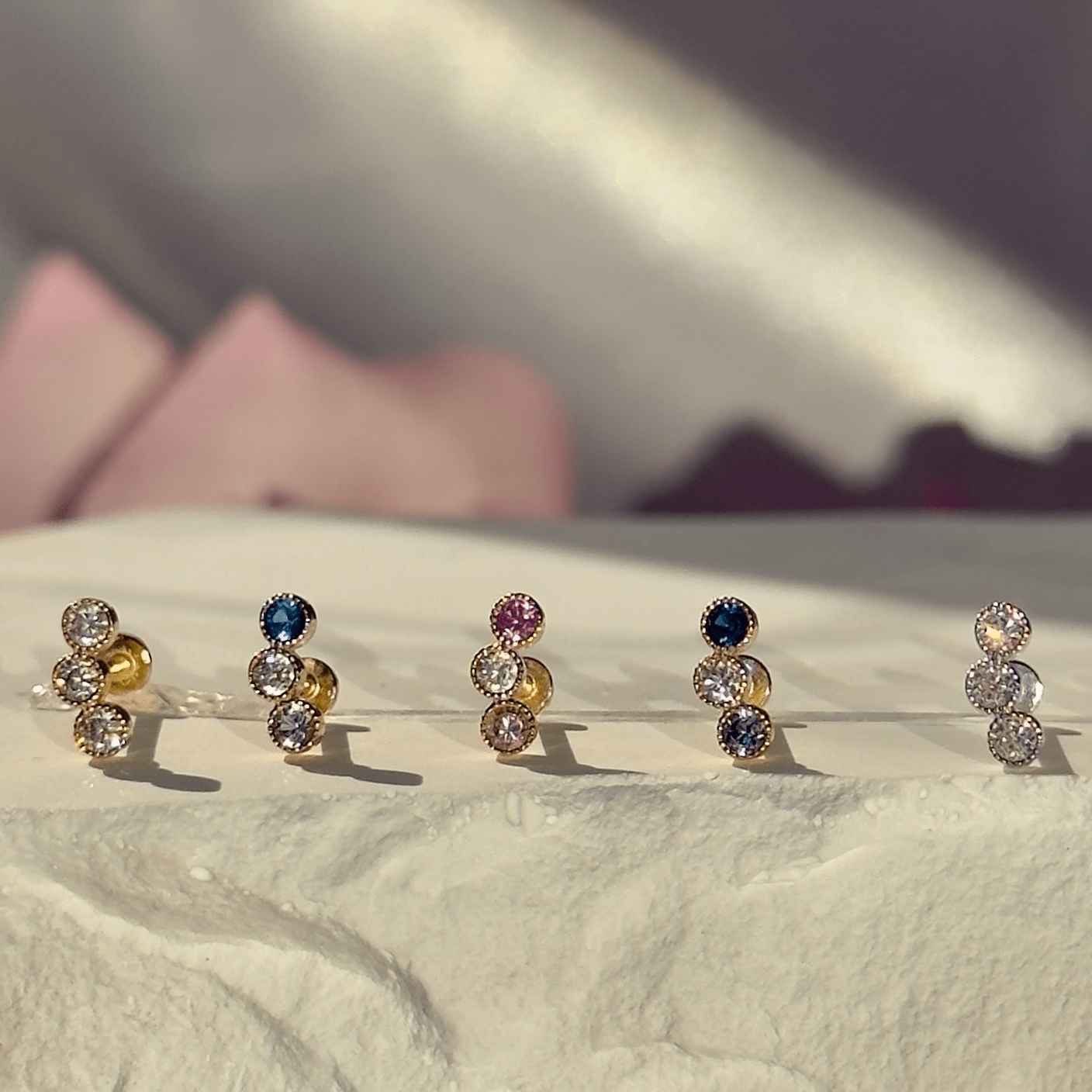 a row of different colored diamond studs on a white surface